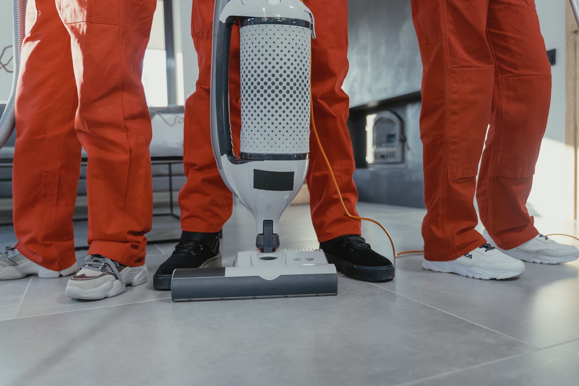 Cleaning crew in orange uniforms with a vacuum cleaner